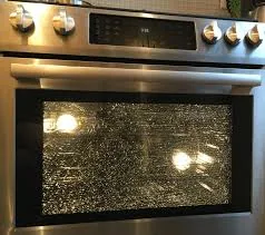 Oven door glass with heavy baked-on grease before cleaning